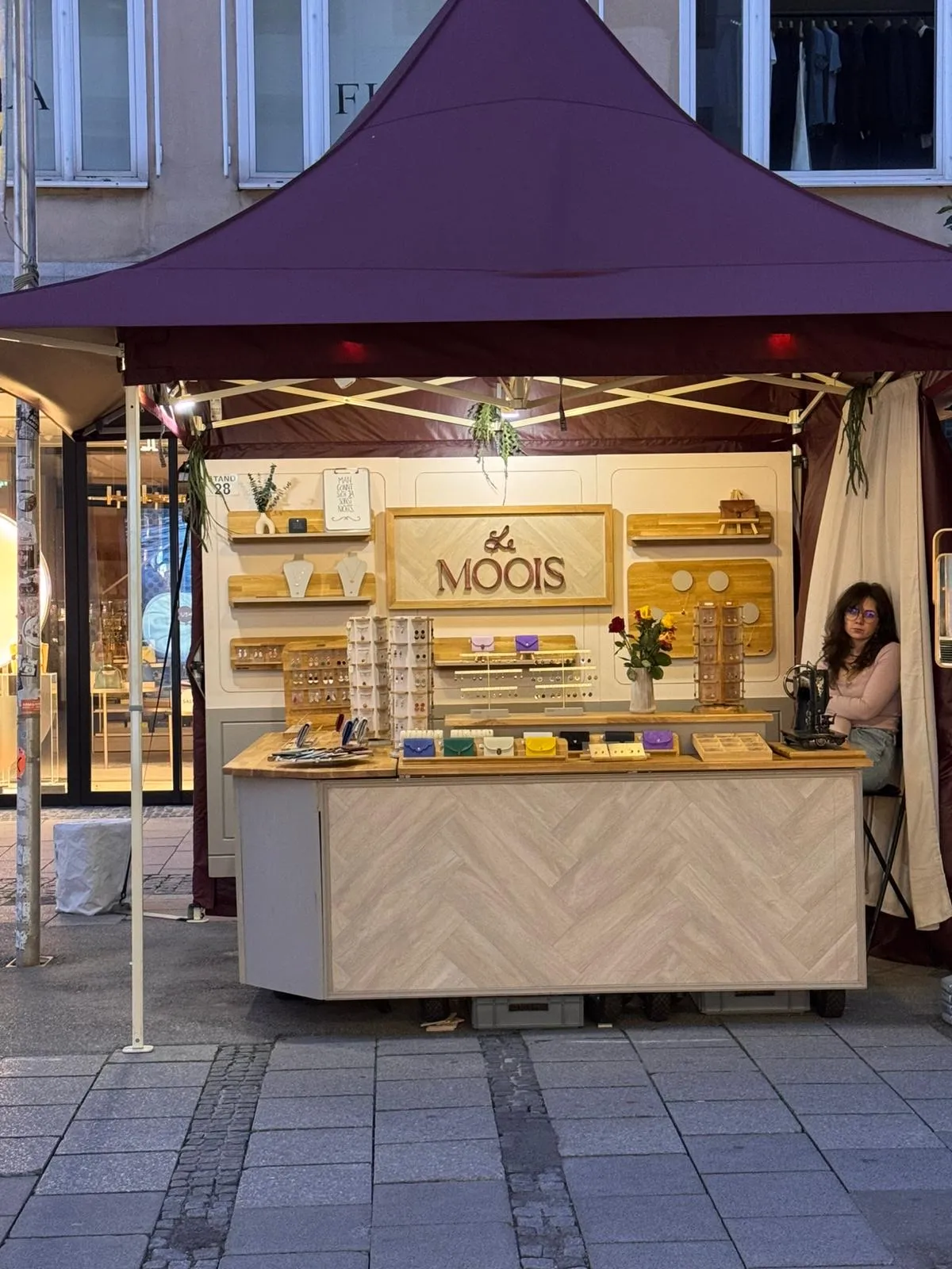 Le-Moois-Marktstand mit burgunderrotem Zeltdach und Besucherinnen